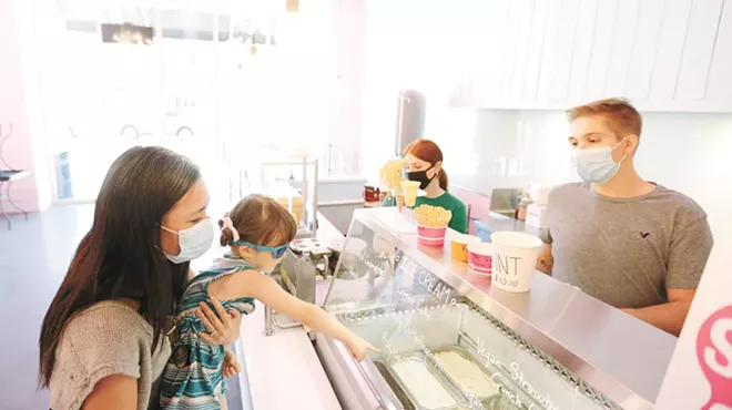 Vanessa Thomsen (left) holds her 3-year-old daughter Mariko as she orders ice cream from Marlin Jones at the Scoop in Kendall Yards.