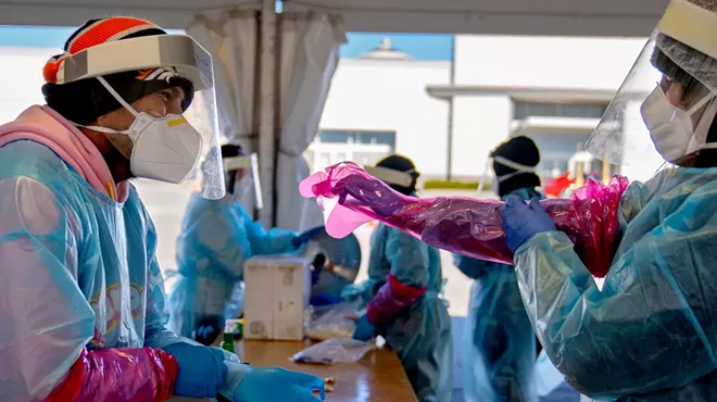 Medical workers don personal protective equipment before testing people for the coronavirus at a mall in Omaha, Neb., Nov. 13, 2020. The seven-day average of new daily cases is more than 140,000, with upward trends in 49 states. Some 30 states added more cases in the last week than in any other seven-day period.