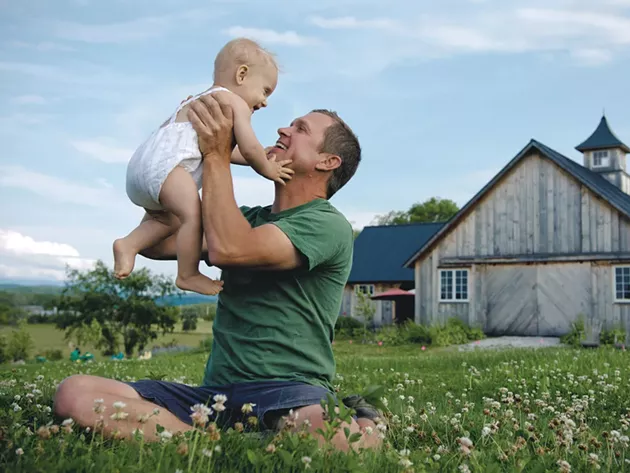 Adam Hausmann, 44, owner of Adam’s Berry Farm in Charlotte, with son Wilder Rye, 9 months - SAM SIMON