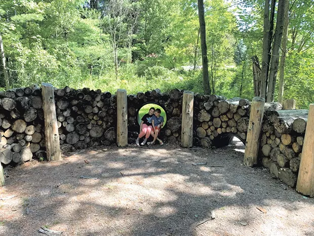 Mira and Theo Novak sit in the spiral wood pile - ALISON NOVAK