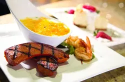 The Cajun Caddy, jumbo shrimp, andouille sausage and cheese grits, front, and Cinnabon cheesecake, back, from the Detroit Cheesecake Bistro in Greektown. - ROBERT WIDDIS