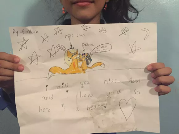 Ferdose Mana holds up a sign she made for her former teacher, who was fired. The third-grader says the last time she saw the teacher was on a Friday during a test. "Pop! She was gone. Every student in my class cried." - ALLIE GROSS