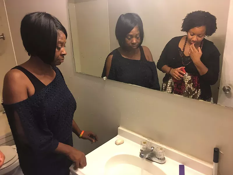 Lillie McGee runs her faucet for Amina Kirk, a legal advocate with the Detroit People's Platform, to show that her hot water doesn't work. - VIOLET IKONOMOVA