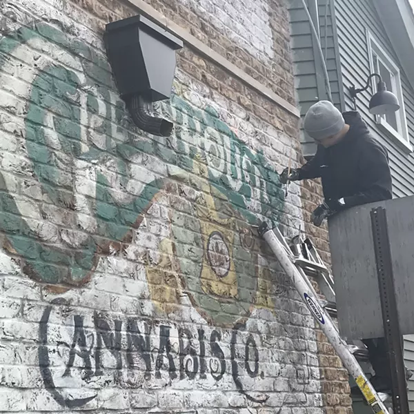 Sign painter Mark Serra adds paints a sign on the Greenhouse of Walled Lake. The store opens for recreational marijuana sales on Saturday. - LARRY GABRIEL