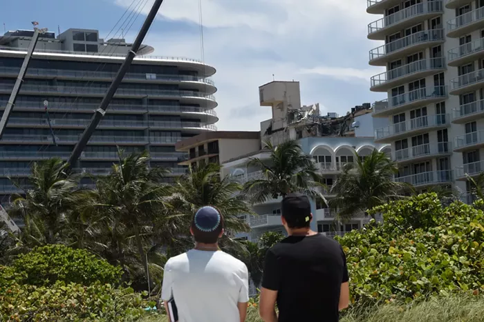 Onlookers on Surfside Breach watch the broken remains of the Champlain Towers South condo before it was torn down this past Sunday. - PHOTO BY MICHELE EVE SANDBERG