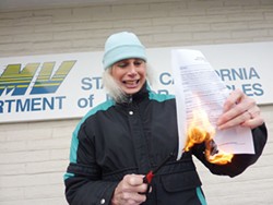 PHOTO BY THADEUS GREENSON. - Joni Kay Rose, 69, burns a form in protest of what she sees as a policy of discrimination in front of the California Department of Motor Vehicles' Eureka office on Feb. 16.