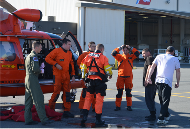 Safely on the ground, survivors and the Coast Guard crew of a MH-65 Dolphin helicopter discuss the rescue of the crew of the vessel “Kellen A” off of Punta Gorda. - US COAST GUARD
