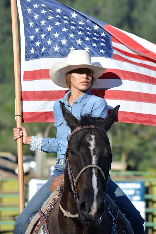 A Native woman carries the flag during the Hoopa Rodeo. - PHOTO BY EVE FREEDMAN