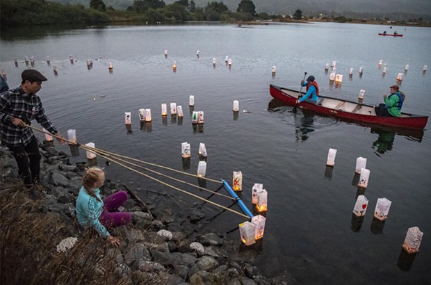 Volunteer Tony Wallin, of Arcata, helped move the lighted lanterns away from the shore into the gentle breeze blowing across Klopp Lake. - PHOTO BY MARK LARSON