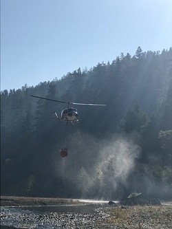 A Cal Fire helicopter pulls water from the Eel River. - KORY BEACH