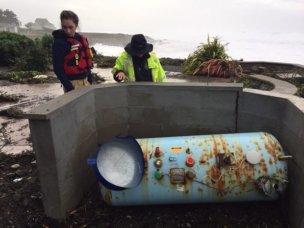 Shelter Cove Fire Crew members, wearing life vests, examine this propane tank  which was shoved off its mountings. - CHERYL ANTONY OF SHELTER COVE FIRE