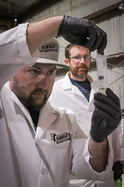 Skyler Palmer, head of cultivation at HendRx Farms, looks on as Humboldt Seed Co. founder Nat Pennington prepares a cannabis sample for testing. - PHOTO BY THADEUS GREENSON