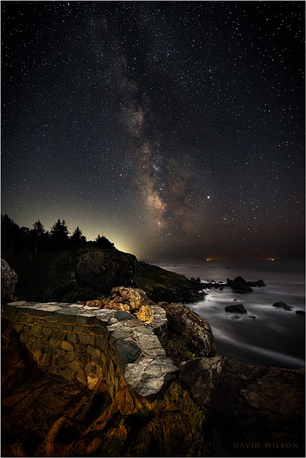 Ramparts stand watch over the great Pacific Ocean at the edge of the continent. The lights of a pair of fishing boats glow in the marine layer’s gloom on the horizon. Patrick’s Point State Park, Humboldt County, California. September 2019. - DAVID WILSON