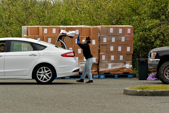 A Cooperation Humboldt volunteer loads a food box into the trunk of a car. - PHIL GUTIERREZ