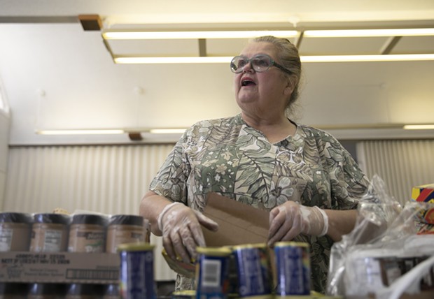 Food bank volunteer Emogene Thomas, 68, arranges cans on a table at Teamsters 315 Hall in Martinez on March 19, 2020. The food bank serves seniors but had about half regular the number of visitors due to coronavirus concerns. - ANNE WERNIKOFF FOR CALMATTERS