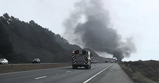 A fire truck rushes to the scene as smoke rises from a fully engulfed vehicle on 101. [Photo from Mary Ann Machi]