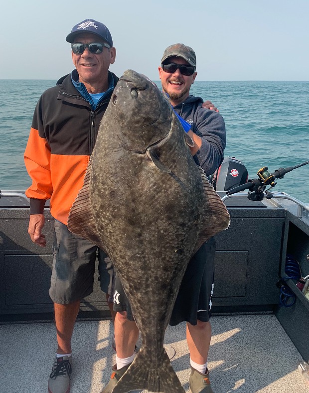 Capt. Rye Phillips of Brookings Fishing Charters holds a Pacific halibut caught Sept. 29 by Joseph Cogin. The fish was just under 60 inches and weighed nearly 100 pounds. It was caught on herring and squid in 220 feet of water off of Brookings. - PHOTO COURTESY OF BROOKINGS FISHING CHARTERS