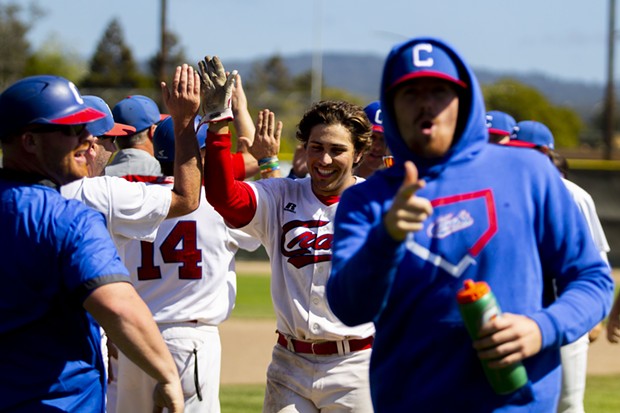 The Humboldt Crabs celebrate their first series win of the season with a 5-4 win over the Lincoln Potters in the third game of the series at Arcata Ballpark as Ethan Fischel (#12) who hit the game winning RBI in the bottom the 13th inning high fives pitching coach Eric Giacone. - PHOTO BY THOMAS LAL