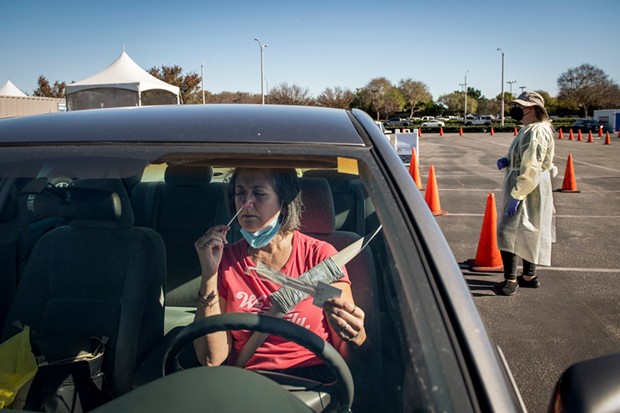 Diane Ahern swabs herself for COVID-19 at a testing site at the Long Beach Airport in Long Beach on Jan. 11, 2022. “I need to get tested every three days to be able to visit my parents at their retirement home,” Ahern said. “I’m nervous.” Photo by Pablo Unzueta for CalMatters - PHOTO BY PABLO UNZUETA FOR CALMATTERS