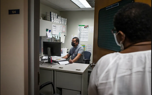 STD Investigator Hou Vang (left) works in his office as Jena Adams (right), Communicable Disease Program Manager, checks in on him on June 8, 2022. - PHOTO BY LARRY VALENZUELA, CALMATTERS/CATCHLIGHT LOCAL