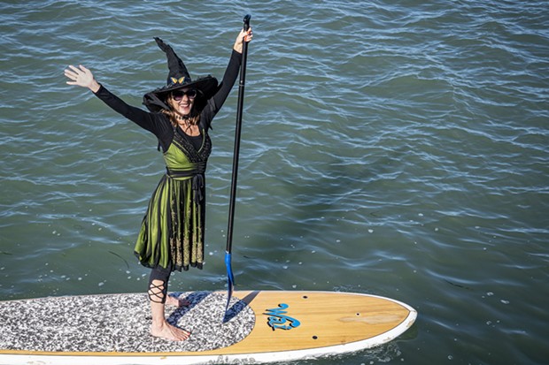 A cheerful witch with a butterfly pin in her hat waved to friends along the Eureka Boardwalk along Humboldt Bay. - PHOTO BY MARK LARSON