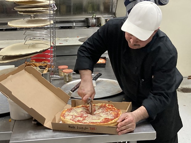 Owner Brett Obra slices a hot Chicago pizza to go. - PHOTO BY JENNIFER FUMIKO CAHILL