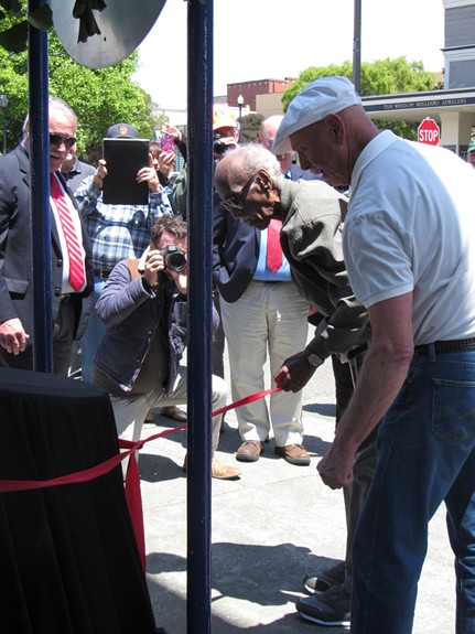 Howard pulls at the ribbon to unveil the new Old Town plaque in his honor. - LINDA STANSBERRY
