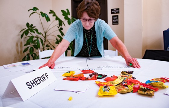 An assistant to Sheriff Billy Honsal prepares to write down residents' concerns on a table strewn with candy for those who missed dinner. - KYM KEMP