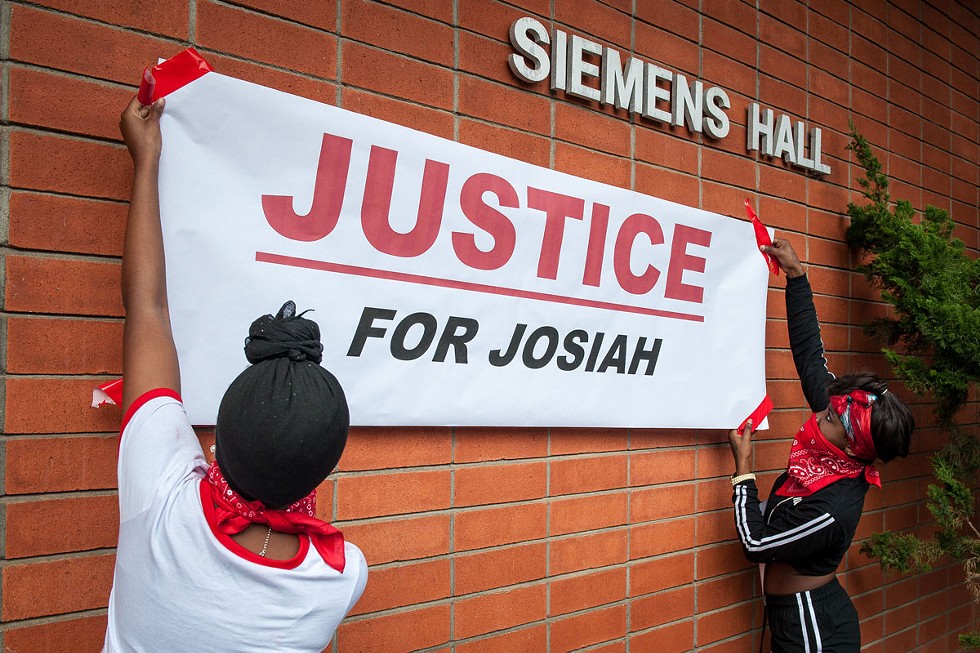 Students hang a "Justice for Josiah" banner on the Humboldt State University quad. At the rally, organizers encouraged those in attendance to scrawl messages of hope, unity and protest on it. - PHOTO BY MARK MCKENNA