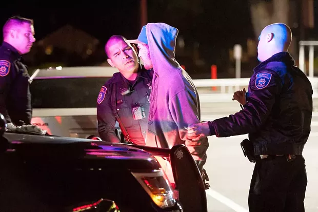 EPD officer Raymond Nunez prepares to arrest a man after he refused to leave the WinCo parking lot. - PHOTO BY MARK MCKENNA