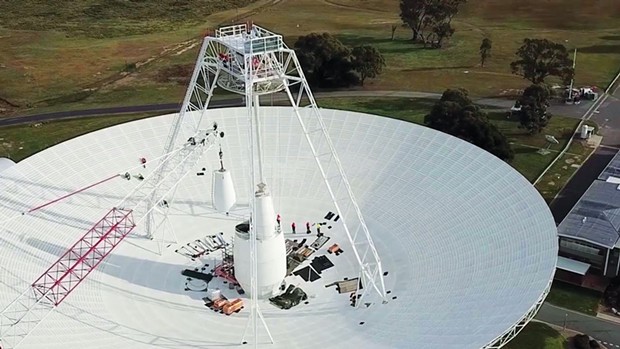 A crane moves one of the white feed cones that house part of the antenna's receivers during the recent seven-month upgrade of the 70-meter Deep Space Station 43 located near Canberra, Australia.