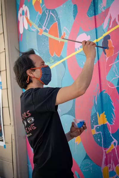 Jose Moreno finishes one of his two murals painted on garage doors in the alley off Henderson Street between E and F streets. - PHOTO BY MARK MCKENNA