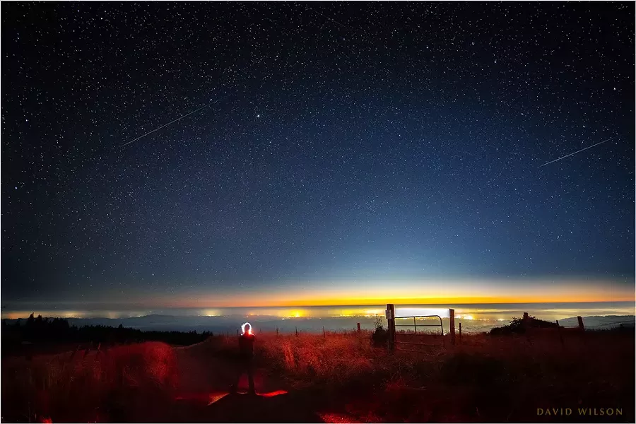 "Self Portrait with Perseid Meteors." The lights of Eureka shine on the Pacific Coast beneath a pair of Perseid meteors in this composite of two images from a timelapse sequence taken during the Perseid meteor shower of 2020 from the hills of Humboldt County on Aug. 12 - DAVID WILSON