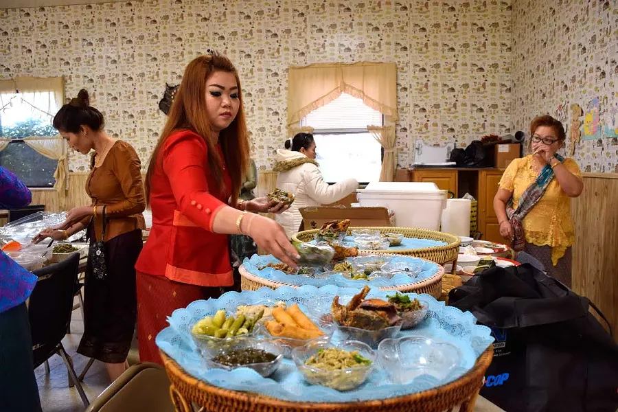 Dishing out Lao specialties onto katoke tables for the monks. - PHOTO BY JENNIFER FUMIKO CAHILL