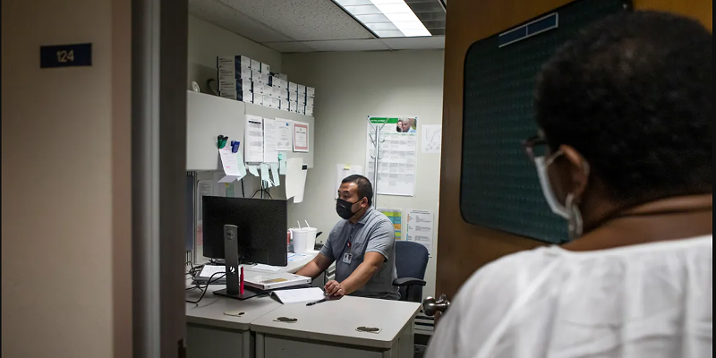 STD Investigator Hou Vang (left) works in his office as Jena Adams (right), Communicable Disease Program Manager, checks in on him on June 8, 2022.
