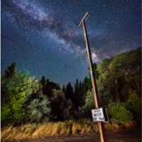 “High Water Dec 1964,” reads the sign at chest level. Arrows on the pole draw the eye to the true marker far above. Avenue of the Giants at Weott, Humboldt County, California.