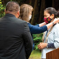 Yurok Tribal Councilmember Sherri Provolt places a necklace made from abalone and bear grass and on U.S. Interior Secretary Deb Haaland as a gift from the tribe during Haaland's visit to the North Coast in August.