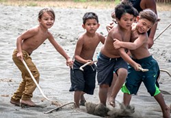 PHOTO BY MARK LARSON - The traditional Stick Game Tournament began with the youngest boys playing the full-contact game that resembles a blend of lacrosse and wrestling. Participants compete tossing the "tossel" either up- or down-river with their sticks toward the goal line to score a point.