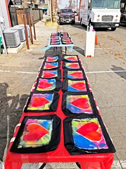 IN PRODUCTION Tables of hand-decorated art bags—created with spray paint and stencils—dry outside Studios on the Park, which will sell the bags full of wine and art goodies as an alternative to its annual Sweet Art in-person luncheon fundraiser. - PHOTOS COURTESY OF STUDIOS ON THE PARK