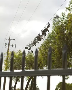 'SHOEFITI': Architecture major Bradley Williams expounds on how a collection of shoes hanging from the telephone wires over a common shortcut for students was elevated to “public art.” When the city created a fence to block off the footpath, the shoe sculpture changed from an evolving part of the landscape to a cordoned-off curiosity. - PHOTO BY STEVE E. MILLER