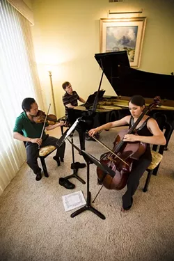 THREE'S HARMONY: Scott Yoo (left), John Novacek (middle), and Madeleine Kabat (right) rehearse one of Russian composer Georgy Sviridov’s piano trios at the home of festival sponsor Samantha Curran. - PHOTO BY HENRY BRUINGTON