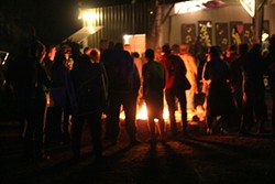 GATHER &lsquo;ROUND THE FIRE :  Campers warm up before the start of a Hot Licks Dance concert. - PHOTO BY GLEN STARKEY