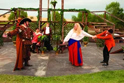 THE CLOWN AND THE COUNTRY WENCH: The pompous Spanish knight Don Armado (David Hance, left) captures the country wench Jacquenetta (Krystal Kirk, being dragged) whom he loves, as a punishment for the clown Costard (Sean Peters, seated in the background), whom she loves. - PHOTO BY STEVE E. MILLER