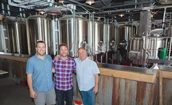 FAMILY TRADITION: From left, Figueroa Mountain Brewing Co. Arroyo Grande Taproom head brewer David Trailles; founder/owner Jaime Dietenhofer; and his father, brewery owner Jim Dietenhofer, pose for a photo inside their newly constructed taproom opening Father’s Day weekend. - PHOTO BY KAORI FUNAHASHI