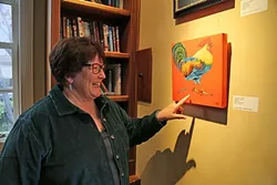 CHICKEN, IT’S WHAT’S FOR ART: Ethel Landers, the volunteer art gallery curator for the GALA Center in San Luis Obispo, stands by her oil painting, Lost it in a tiff, which features a chicken that has lost a feather. The piece is currently hanging in the gallery on Palm Street. - PHOTO BY DYLAN HONEA-BAUMANN