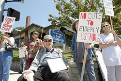 NOT WITHOUT A FIGHT : If state budget cuts go through, 71-year-old Dale Grube (center, seated) worries he’ll lose the freedom of his apartment, because without his caretaker he’ll be forced to live in a convalescent home. - PHOTO BY STEVE E. MILLER