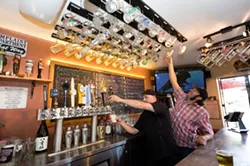DRINK LIKE A LOCAL: Baywood Ale House Manager Christopher Mayes (left) and Owner Chad Carroll reach for their coveted “local” mugs, of which there are 100. Currently, 300 people are waiting to get on the loyalty program list. - PHOTO BY KAORI FUNAHASHI