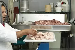 6: : Using a grinder from 1967 that Antonio refurbished, Tesero adds a specific mixture of 20% pork belly and 80% shoulder and leg meat to begin the process of making the salamis.