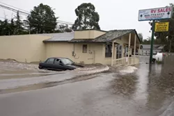 DROWNING : Drainage problems caused massive flooding and damage at Pacific Coast RV in Pismo Beach. From left to right: Mechanic Daren Lenton drives his car off the flooded lot; owner Shaun Brewer wades through water he said was twice as high the night before; and employee Craig Mase uses a forklift to drag an RV off the lot. - PHOTO BY STEVE E. MILLER