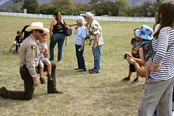 GOOD GUY WITH A GUN: SLO County Sheriff Ian Parkinson takes a knee for a photo op with a young admirer. - PHOTO BY GLEN STARKEY